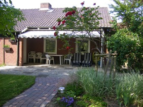 sunny terrace with awning and garden furniture, flowerns in the front